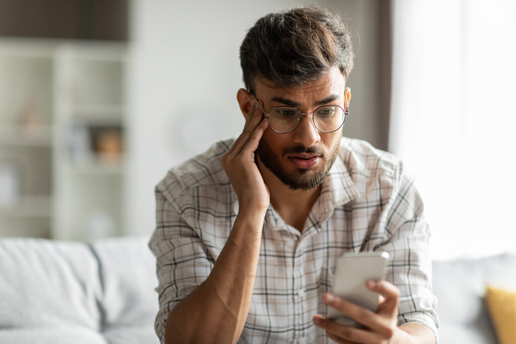 man frustrated while looking at phone